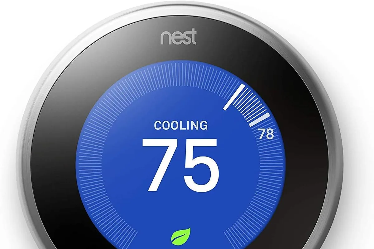 A smart thermostat mounted on a hallway wall with a digital display