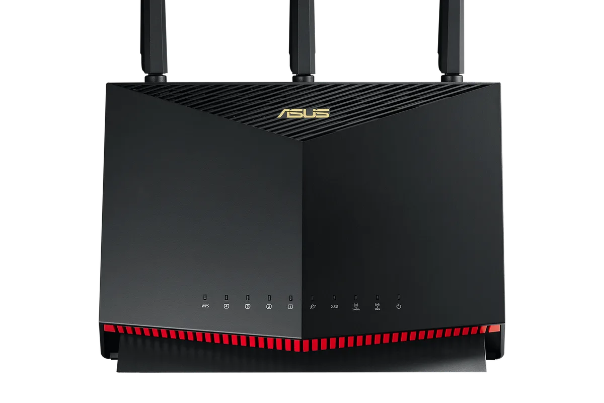A gaming router with antennas on a desk next to a PC with RGB lighting
