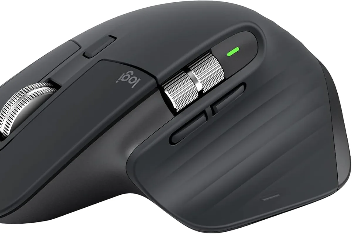 A wireless mouse on a desk next to a laptop